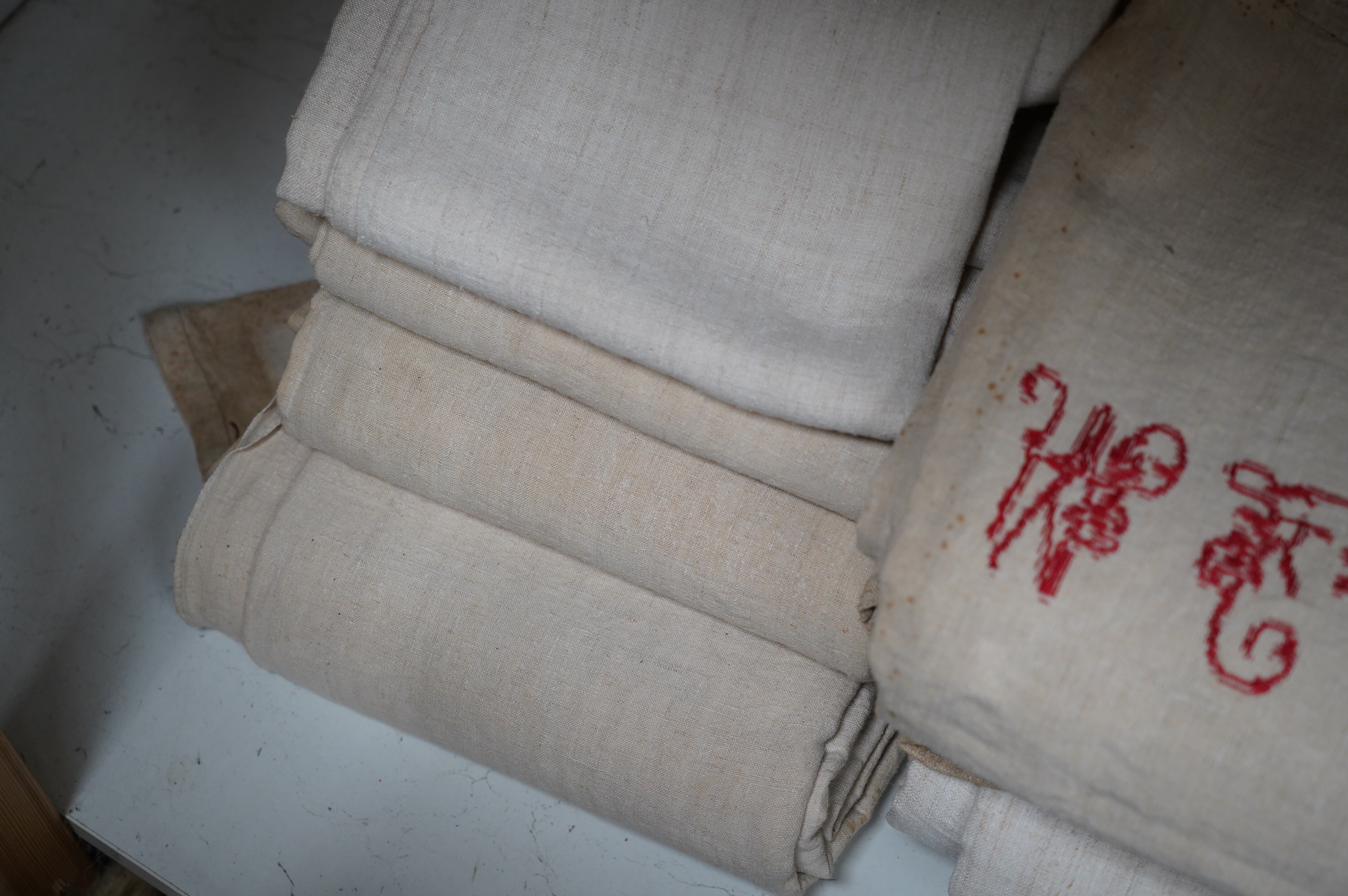 Fourteen French provincial coarse linen sheets, mostly with red embroidered monograms